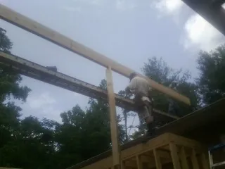 Carpenter setting a ridge beam over a new addition frame — Ice Dam Removal by Roofing Brothers in Flatonia