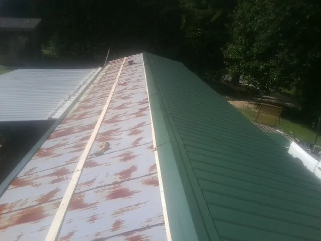 Old rusted panels beside newly installed green metal roofing — Wind Damage Roof Repair by Roofing Brothers in Flatonia