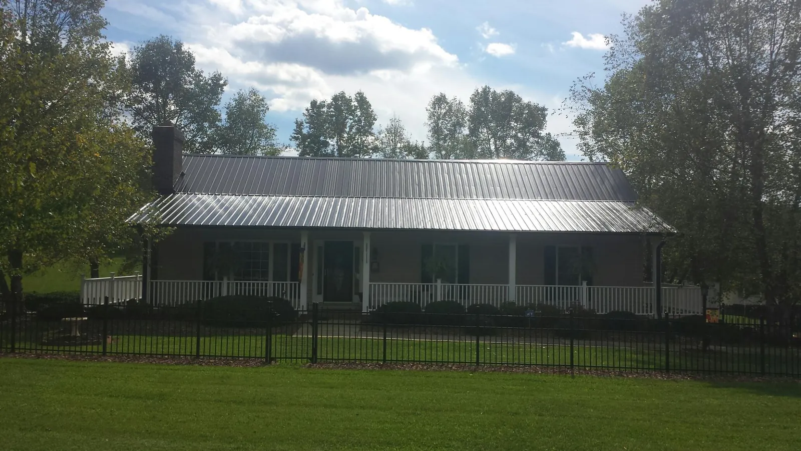 Gray metal roof on a brick ranch with a full width front porch — Gutter Guard Installation work by our crew in Flatonia