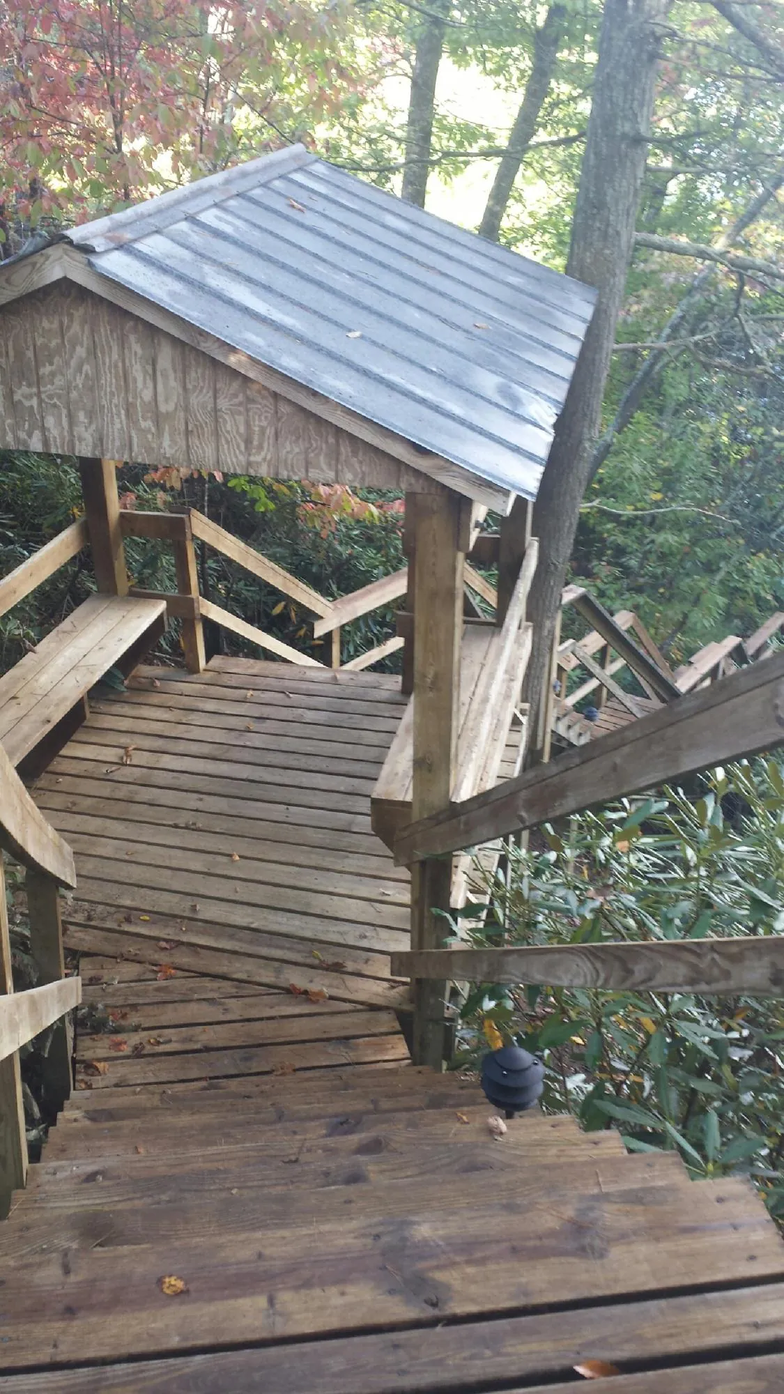 Metal roofed shelter over wooden steps on a wooded walkway — Skylight Repair & Installation work by our crew in Flatonia